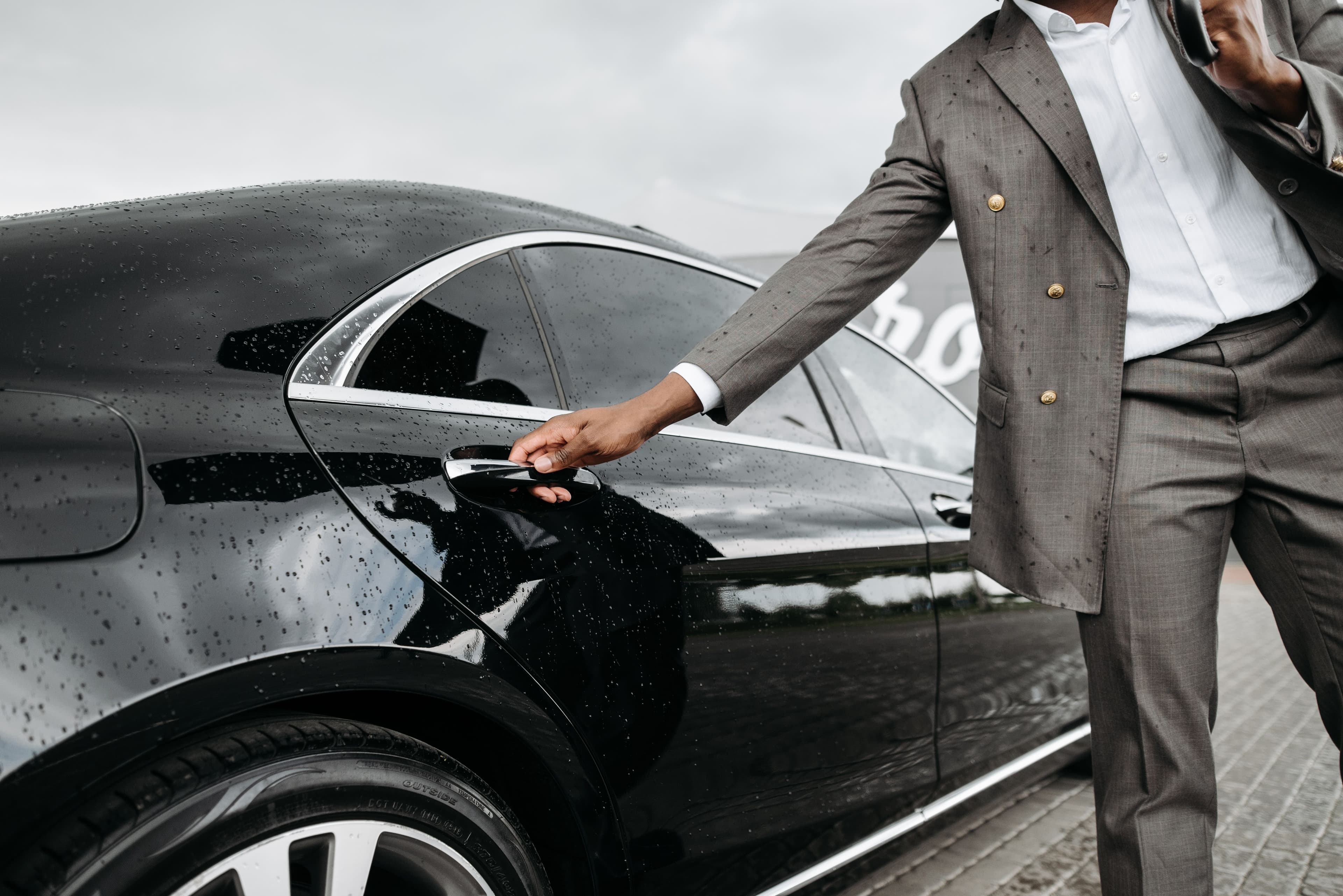 Private chauffeur opening a luxury car door for a guest